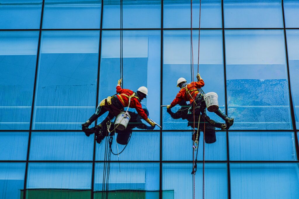 pexels-photo-4767875 Window cleaners using safety harnesses on a skyscraper facade, captured in Vietnam.